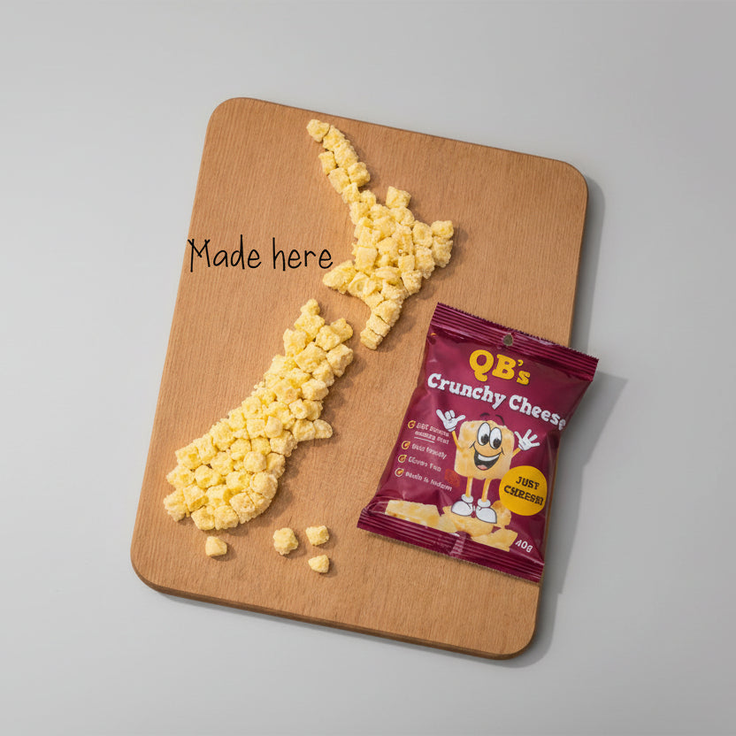 QB's Crunchy Cheese snack package on a wooden board with cheese crumbles shaped like New Zealand.