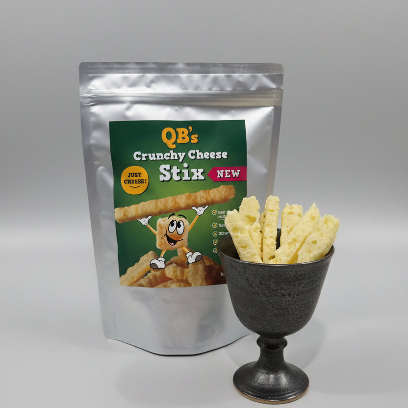 QB's Crunchy Cheese Stix packaging with a handful of Stix In a cup with a neutral background